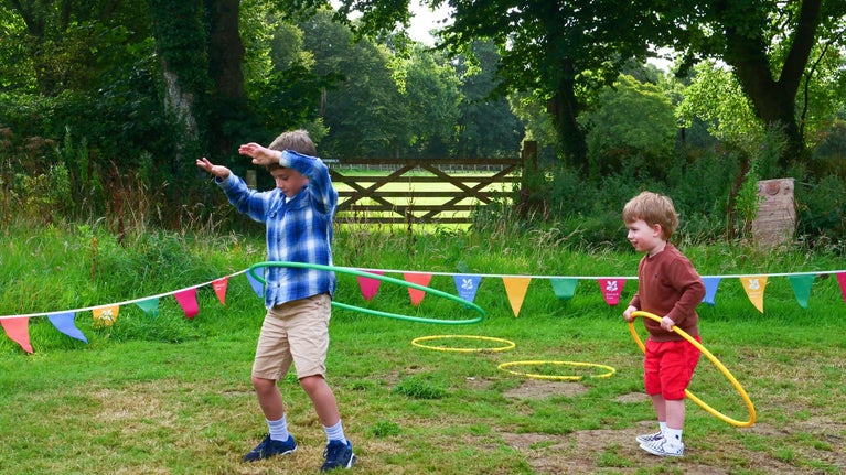 An image of two children hula hooping in the field at Trerice as part of their Summer of Play activities